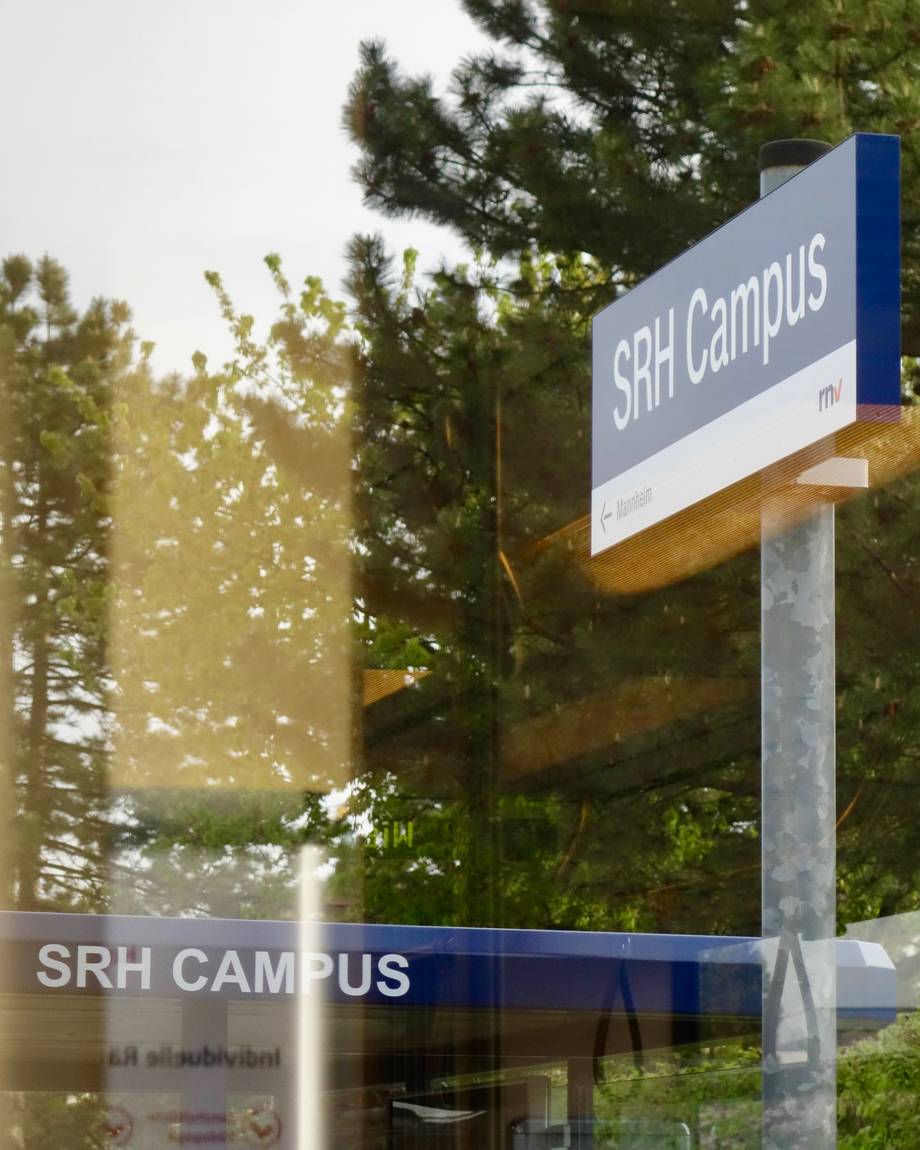 Haltestellenschild SRH Campus in der Spiegelung eines Bahnfensters