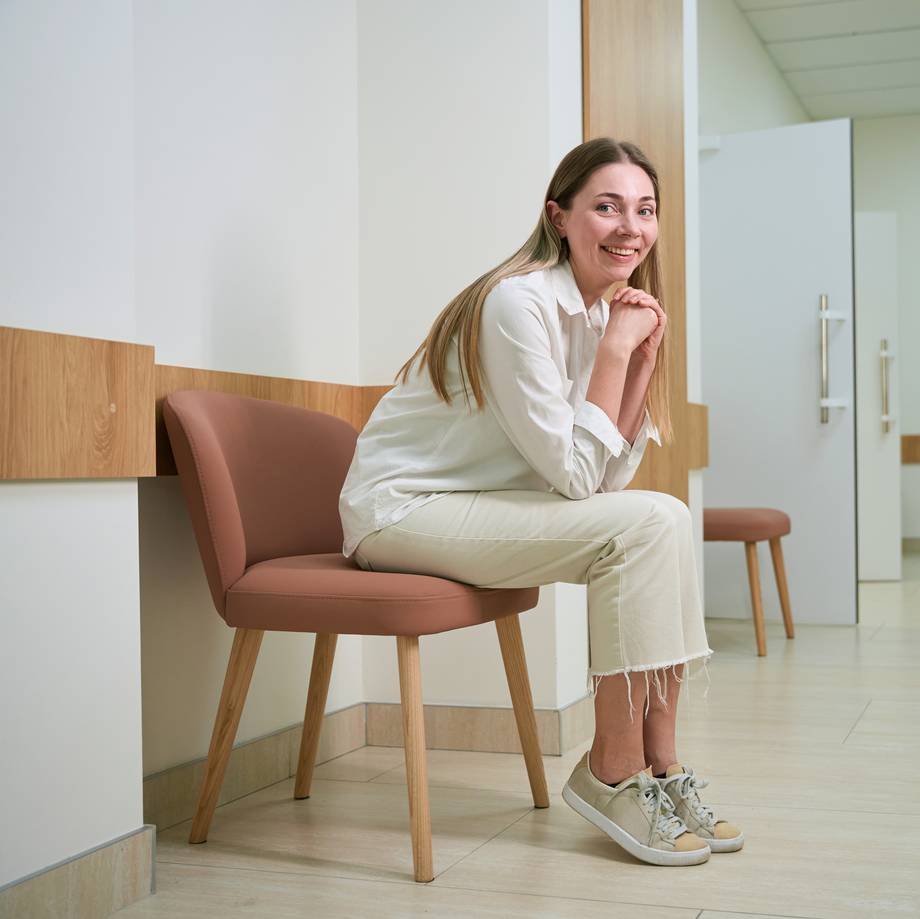 Patientin sitzt im Wartebereich und lächelt
