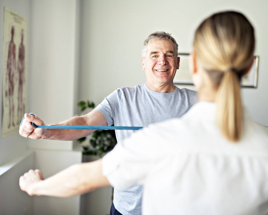 Patient macht orthopädische Übung mit Elastikband nach