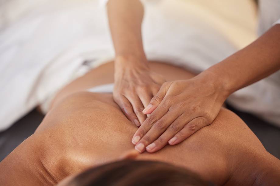 Bildausschnitt der Hände einer Masseurin und des Rücken einer Patientin