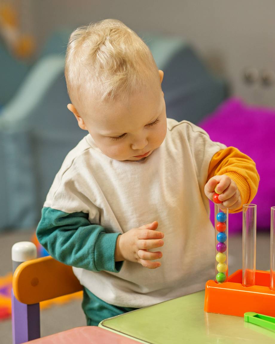 Kleiner blonder Jung spielt mit Kugeln