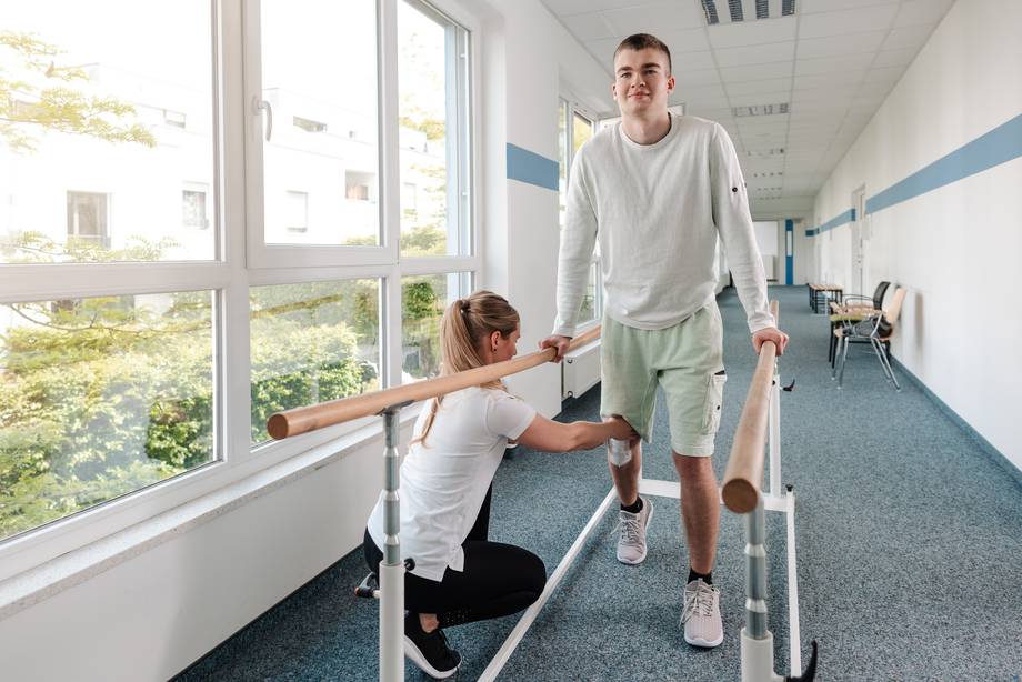 Junger Mann mach Geh-Übungen nach einer Sportverletzung