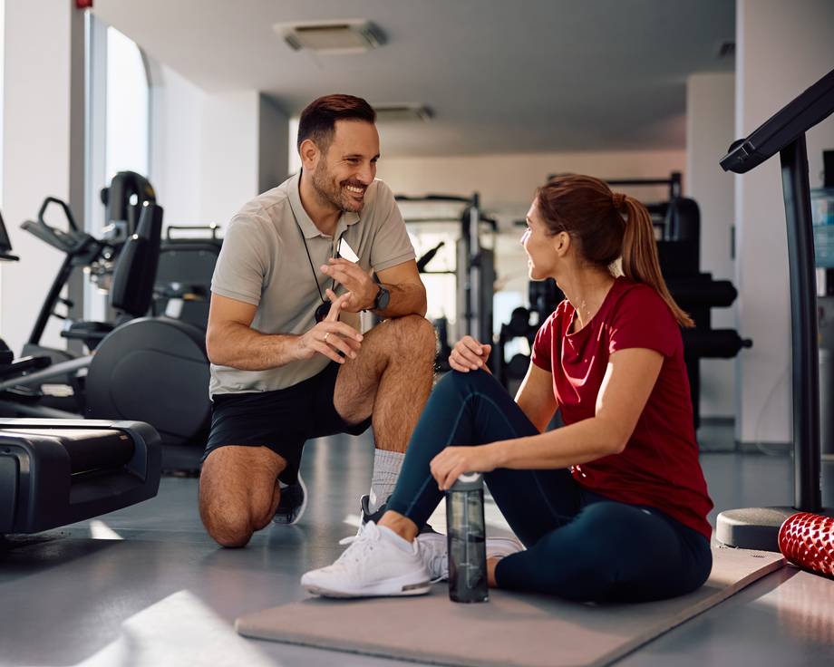 Physiotherapeut und junge Frau, die während des Sporttrainings reden.