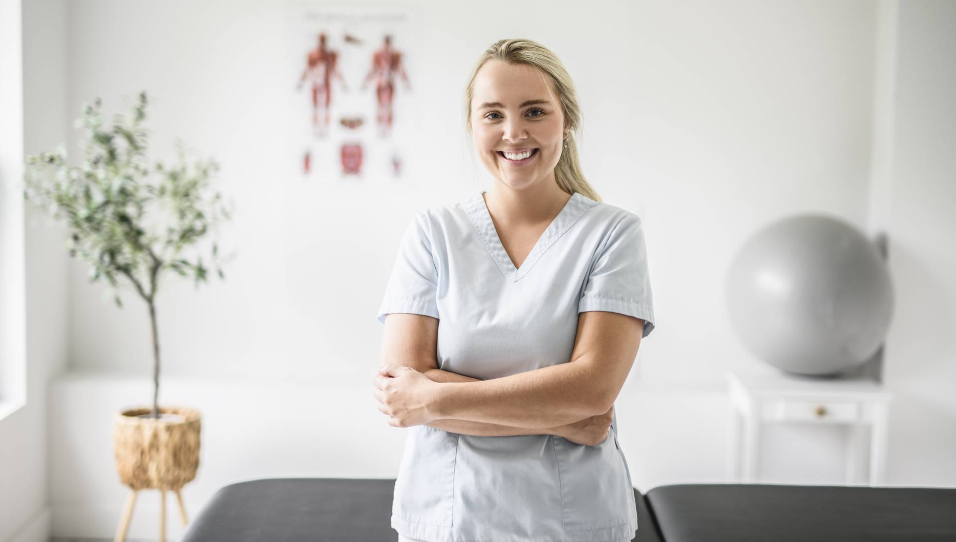 Blonde Physiotherapeutin bei der Arbeit und lächelt in die Kamera