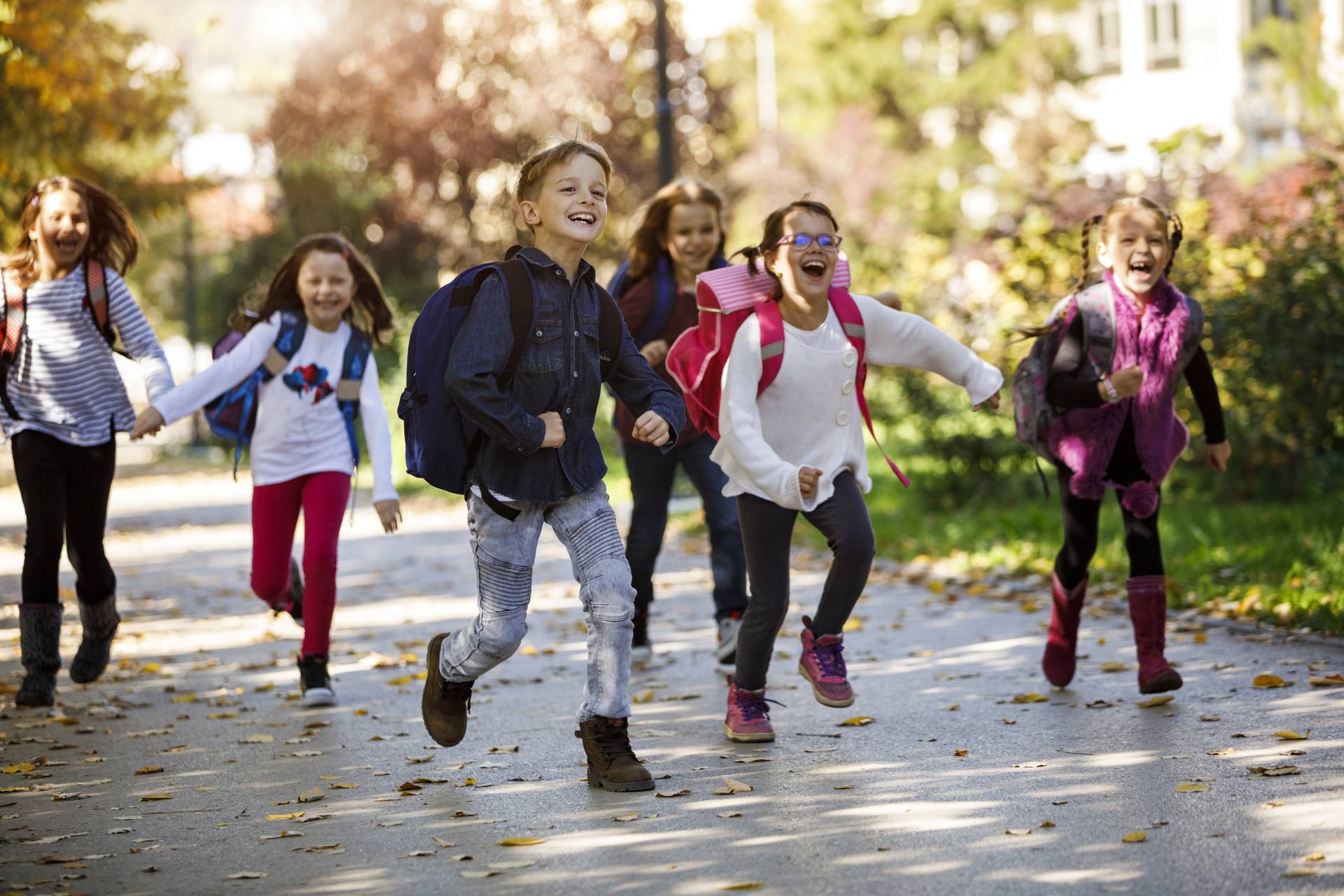 Eine Gruppe von Kindern läuft lachend und spielend in einem Park.
