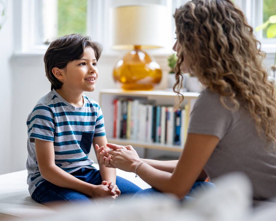 Kleiner Junge spricht mit seiner Logopädin und lächelt