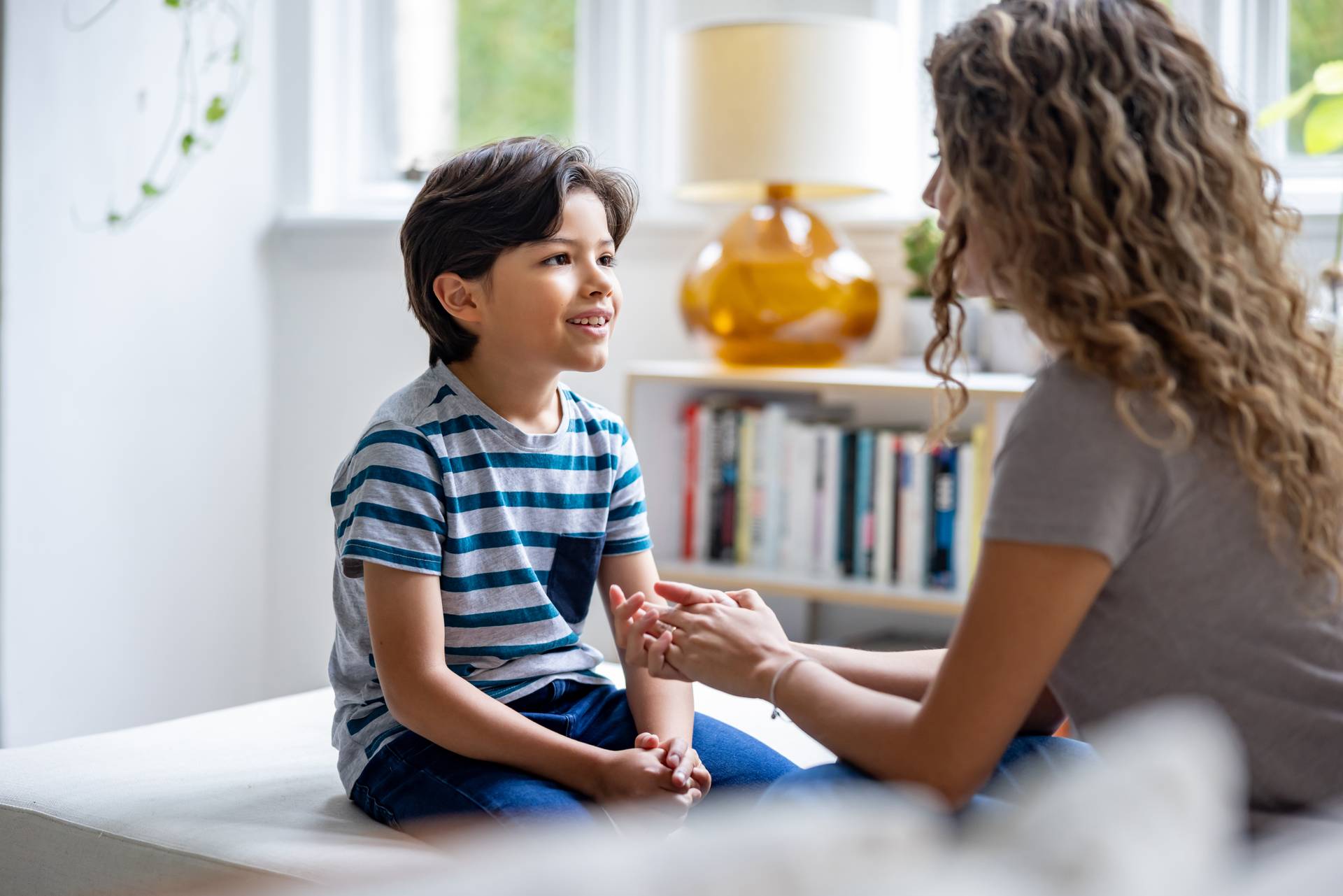 Logopädin redet mit einem Jungen, der ihr gegenüber sitzt während der Therapie